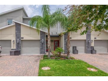 Charming townhome exterior features a red front door, two-car garage, and well-manicured lawn at 783 Ocean Course Ave, Davenport, FL 33896