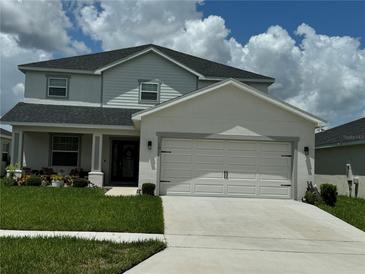 Two-story home featuring a two-car garage, well-maintained lawn, and manicured landscaping at 1016 Cascade Dr, Davenport, FL 33837
