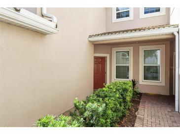 Exterior entrance showcasing well-maintained landscaping, a covered porch, and brick walkway at 1225 Bella Cara Ct # 1, Davenport, FL 33896