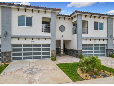 Modern townhouses featuring a two-car garage, balcony, and decorative stone accents at 1870 Brentwood Ct, Davenport, FL 33837