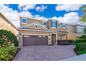 Two-story home featuring a brown two-car garage, brick driveway, and manicured landscaping under a bright blue sky at 321 Lasso Dr, Kissimmee, FL 34747