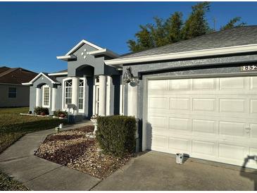 Charming single-story home featuring a gray exterior, white trim, arched windows, and a two-car garage at 852 Adour Dr, Kissimmee, FL 34759