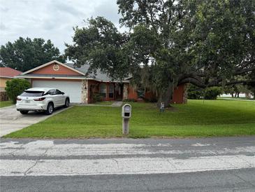 Charming one-story home with a large tree in front and a well-maintained lawn and a white SUV in the driveway at 925 Derbyshire Dr, Kissimmee, FL 34758