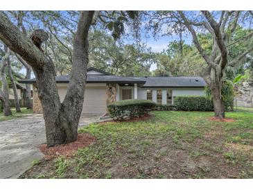 Charming single-story home with stone accents, a lush yard, and mature trees providing shade at 9905 Nicoma Ln, Orlando, FL 32817