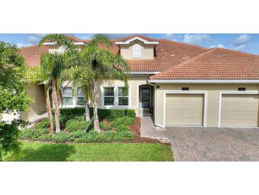 Charming home featuring a red tile roof, a two-car garage and palm trees accenting the landscaped front yard at 1064 Quaker Ridge Ln, Davenport, FL 33896