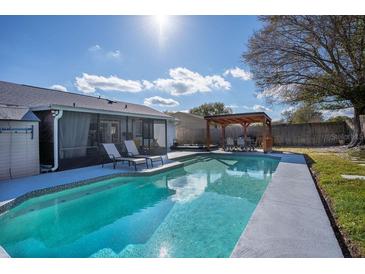 Inviting backyard pool with lounge chairs, outdoor dining under pergola, and well-maintained landscaping at 1375 Springfield St, Kissimmee, FL 34744