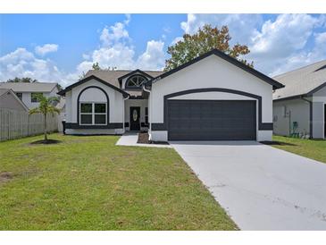 Charming single-story home with a two-car garage, well-manicured lawn, and black and white color scheme at 14639 Musket Fire Ln, Orlando, FL 32837