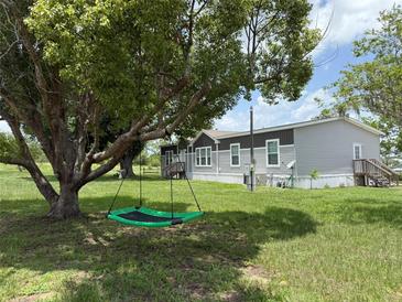 Manufactured home with a brown and gray exterior, set in a large lot with a tree swing at 15311 Johns Lake Rd, Clermont, FL 34711