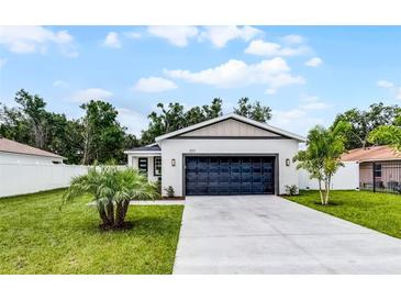 Charming single-story home features a well-manicured lawn and a modern garage door at 2211 Simmons St, Leesburg, FL 34748