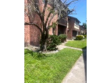 Charming exterior view of townhomes with brick and wood, mature landscaping, and manicured lawn on a sunny day at 5144 Picadilly Circus Ct # 2, Orlando, FL 32839