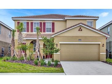 Charming two-story home featuring a well-manicured lawn, beautiful landscaping, and a two-car garage at 7622 Oakmoss Loop, Davenport, FL 33837