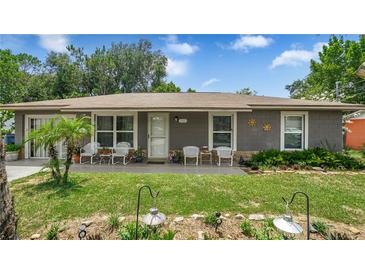 Charming single-story home featuring a well-manicured lawn and cozy front porch with seating at 505 Oak Dr, Tavares, FL 32778