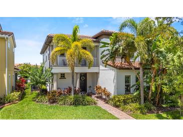 Charming two-story home featuring a cozy balcony and lush, tropical landscaping at 10067 Mere Pkwy, Orlando, FL 32832
