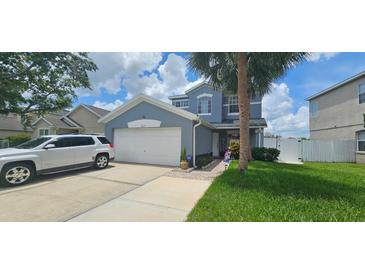 Two-story home featuring a two car garage, palm tree, and manicured front yard at 1827 Meadow Pond Way, Orlando, FL 32824