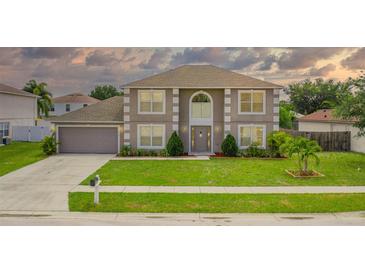 Charming two-story home with a manicured front yard, beautiful landscaping, and an attached two-car garage at 1912 Maury Rd, St Cloud, FL 34771