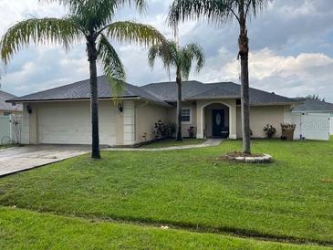 Beautiful single-story home with lush green lawn and mature palm trees at 306 Clermont Dr, Kissimmee, FL 34759