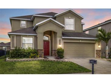 Charming two-story home featuring a two-car garage, red door, and well-maintained landscaping at 3853 Cortland Dr, Davenport, FL 33837
