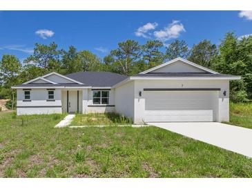 Charming single-story home with a two-car garage, white exterior, and a well-manicured front lawn at 7 Spring Pass, Ocala, FL 34472