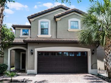 Charming two-story home featuring a tile roof and a two-car garage with tropical landscaping at 8897 Rhodes St, Kissimmee, FL 34747