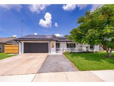 Charming single-story home featuring a gray-tone front door, gray-tone garage, solar panels, and well-maintained landscaping at 12104 Shallot St, Orlando, FL 32837