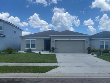 Beautiful single-story home featuring a gray exterior, a two-car garage, and manicured landscaping at 568 Meadow Bend Dr, Davenport, FL 33837