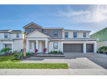 Charming three-story home showcasing manicured landscaping, a three-car garage, and a paved driveway at 2525 Shanti Dr, Kissimmee, FL 34746