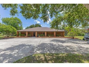 Spacious brick home featuring a circular driveway and mature trees, offering a blend of classic style and natural beauty at 3181 Canter Ln, Kissimmee, FL 34746