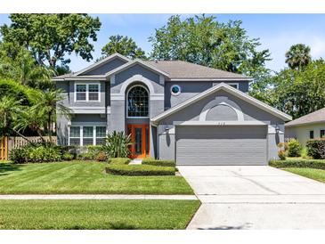 Charming two-story home with a manicured lawn, beautiful landscaping, and an attached two-car garage at 716 Timberwilde Ave, Winter Springs, FL 32708