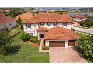 Elegant two-story home featuring a red tile roof, manicured lawn, and a spacious three-car garage at 1776 Bella Lago Dr, Clermont, FL 34711
