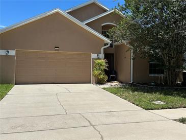 Two-story home with a two-car garage, tan exterior, and a well-manicured front yard with a large tree at 2106 Congress Ln, St Cloud, FL 34769