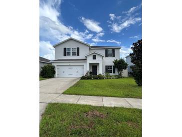 Charming two-story home with a well-manicured lawn and beautiful landscaping at 293 Fiddlewood Ct, Davenport, FL 33837