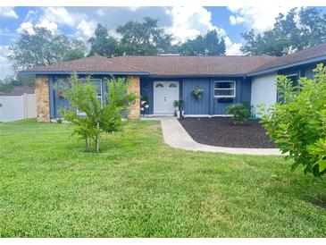 Charming blue home with stone accents, lush lawn, and walkway to the front door at 421 Bridle Path, Casselberry, FL 32707
