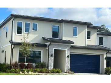 Modern two-story home with a stone entryway, dark blue garage door, and well-maintained landscaping at 1283 Butterfly, Davenport, FL 33837