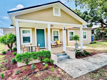 Charming home featuring a cozy front porch, a blue door, and freshly landscaped yard with plants and flowers at 13 E 8Th St, Frostproof, FL 33843