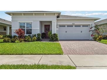Charming home featuring a manicured lawn, brick paver driveway, and two-car garage at 2621 Redblush Ter, St Cloud, FL 34772