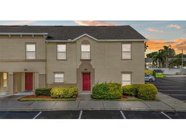 Tan two-story townhouse featuring a red front door, tidy landscaping, and convenient parking at 2867 Club Cortile Cir, Kissimmee, FL 34746