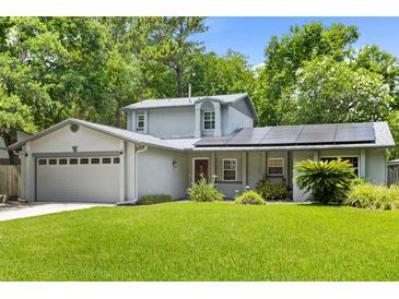 Charming home featuring solar panels, a well-maintained lawn, and lush landscaping, enhancing curb appeal at 878 Elgin Dr, Winter Springs, FL 32708