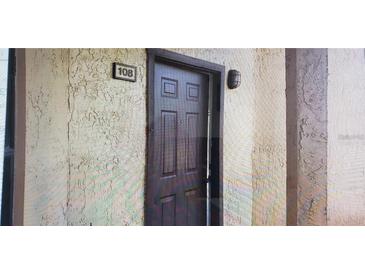 Unit 108 features a solid wood front door with a textured exterior wall and sconce lighting at 2002 Cascades Blvd # 108, Kissimmee, FL 34741
