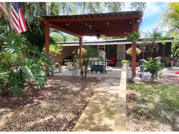 Inviting patio with pergola and outdoor grill, surrounded by lush landscaping and an American flag at 2082 Starboard Dr, Geneva, FL 32732