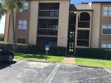 Multi-level condominium building featuring private balconies, well-maintained landscaping, and designated accessible parking at 2202 Cascades Blvd # 201, Kissimmee, FL 34741