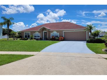 Charming single-story home features a red roof, two-car garage, manicured lawn, and mature landscaping at 2357 Great Harbor Dr, Kissimmee, FL 34746