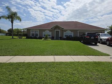 Well-maintained single-story home featuring a lush green lawn and mature landscaping at 2357 Great Harbor Dr, Kissimmee, FL 34746