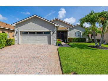 Charming single-story home with a brick driveway, two-car garage, and a beautifully manicured lawn at 4056 Ashton Club Dr, Lake Wales, FL 33859