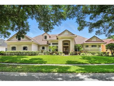 Elegant single-story home featuring lush landscaping, manicured lawn, and a beautiful light beige stucco exterior at 8214 Lake Serene Dr, Orlando, FL 32836