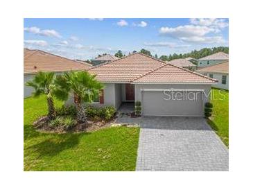 Charming single-story home featuring a tile roof, manicured lawn, paver driveway, and a two-car garage at 1416 Oak Marsh St, Davenport, FL 33837