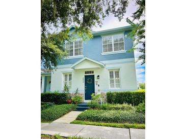 Charming two-story home boasts a landscaped yard, blue accents, and a welcoming front door with wreath at 2862 Grasmere View Pkwy, Kissimmee, FL 34746