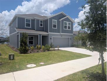 Two-story home featuring modern siding, well-kept lawn, and attached two-car garage at 5793 Gingham Dr, Kissimmee, FL 34758