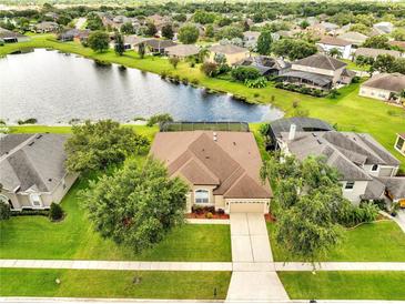 Beautiful aerial view of the home with a well manicured lawn near a tranquil pond and lush landscaping at 1902 Tumblewater Blvd, Ocoee, FL 34761