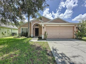 Charming single-Gathering home featuring a two-car garage and a well-maintained front lawn with mature trees at 838 Sandy Ridge Dr, Davenport, FL 33896