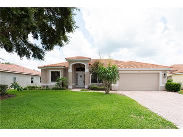 Charming single-story home featuring a well-manicured lawn, a red-tiled roof, and an attached two-car garage at 406 Cinnamon Dr, Kissimmee, FL 34759